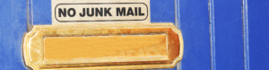 A gold letter box on a blue door with a sign that reads no junk mail.