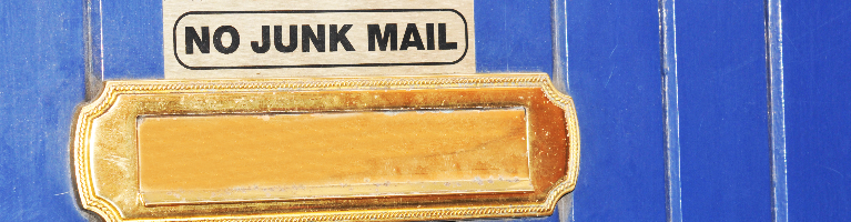 A gold letter box on a blue door with a sign that reads no junk mail.